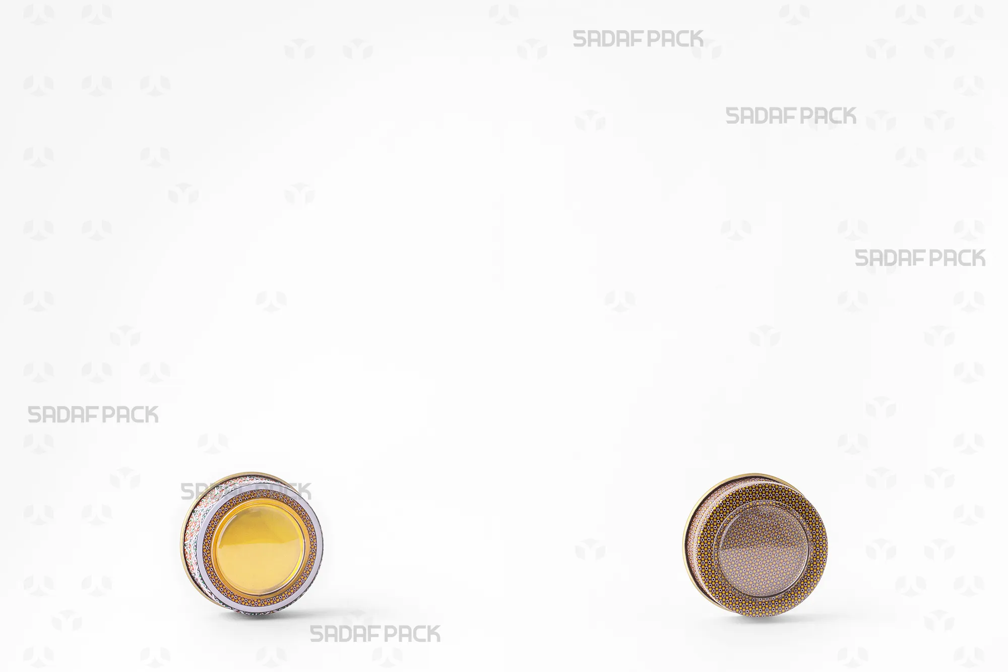 A side-by-side comparison of two different 1-gram metal tin designs, showcasing the distinct patterns and colors used for Sadaf Pack's premium saffron packaging.