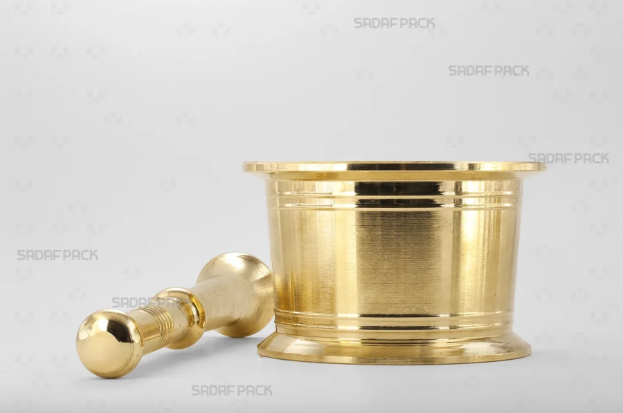 The sturdy brass pestle rests beside the Sadaf Pack Traditional Mortar 130, displaying the complete, well-matched set designed for achieving a fine powder from various spices and saffron.