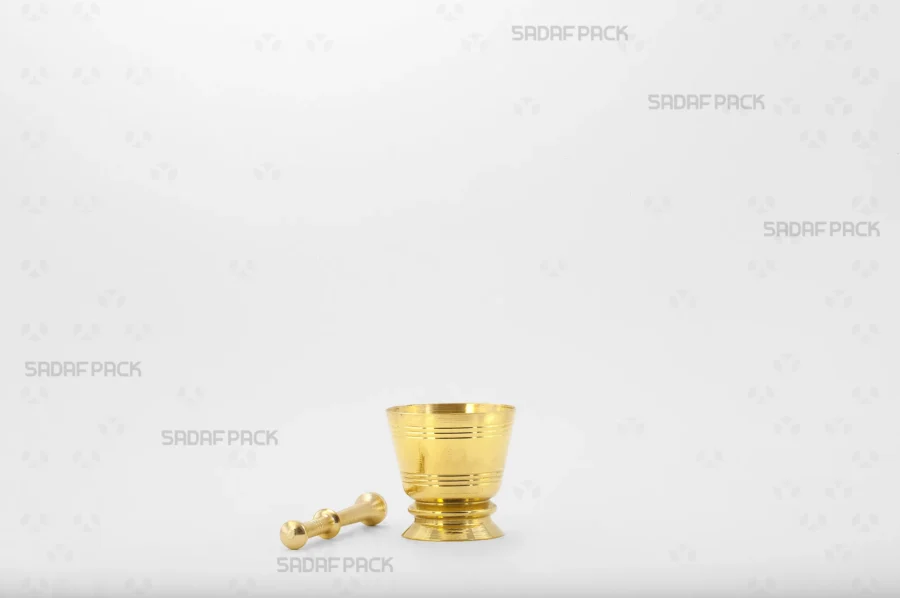 The elegant Sadaf Pack Cup Mortar 39 made from high-quality brass, with its matching pestle placed neatly beside it. Both pieces feature detailed circular engravings, showcasing the set's craftsmanship.