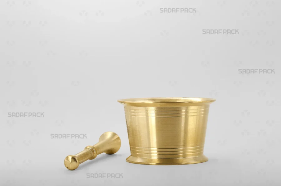 The Sadaf Pack Traditional Mortar 85 is displayed with its matching brass pestle resting beside it, highlighting the unique, detailed circular lines engraved on both the mortar and pestle.