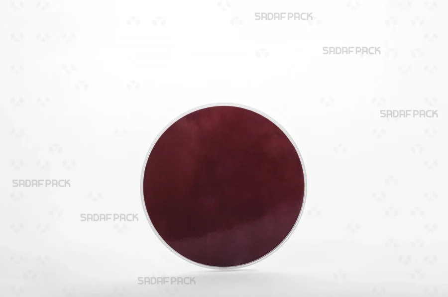 Three-quarter angle view of the 9.5 España round poly-crystal container with crimson Cardboard Pad 9.5 inside container