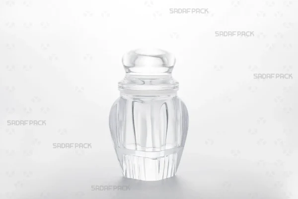 منظر بزاوية ثلاثة أرباع لعبوة كريستال گوهر 4 بقاعدة مرتفعة من صدف باك، يعرض تصميمها الأنيق لتغليف الزعفران الفاخر.