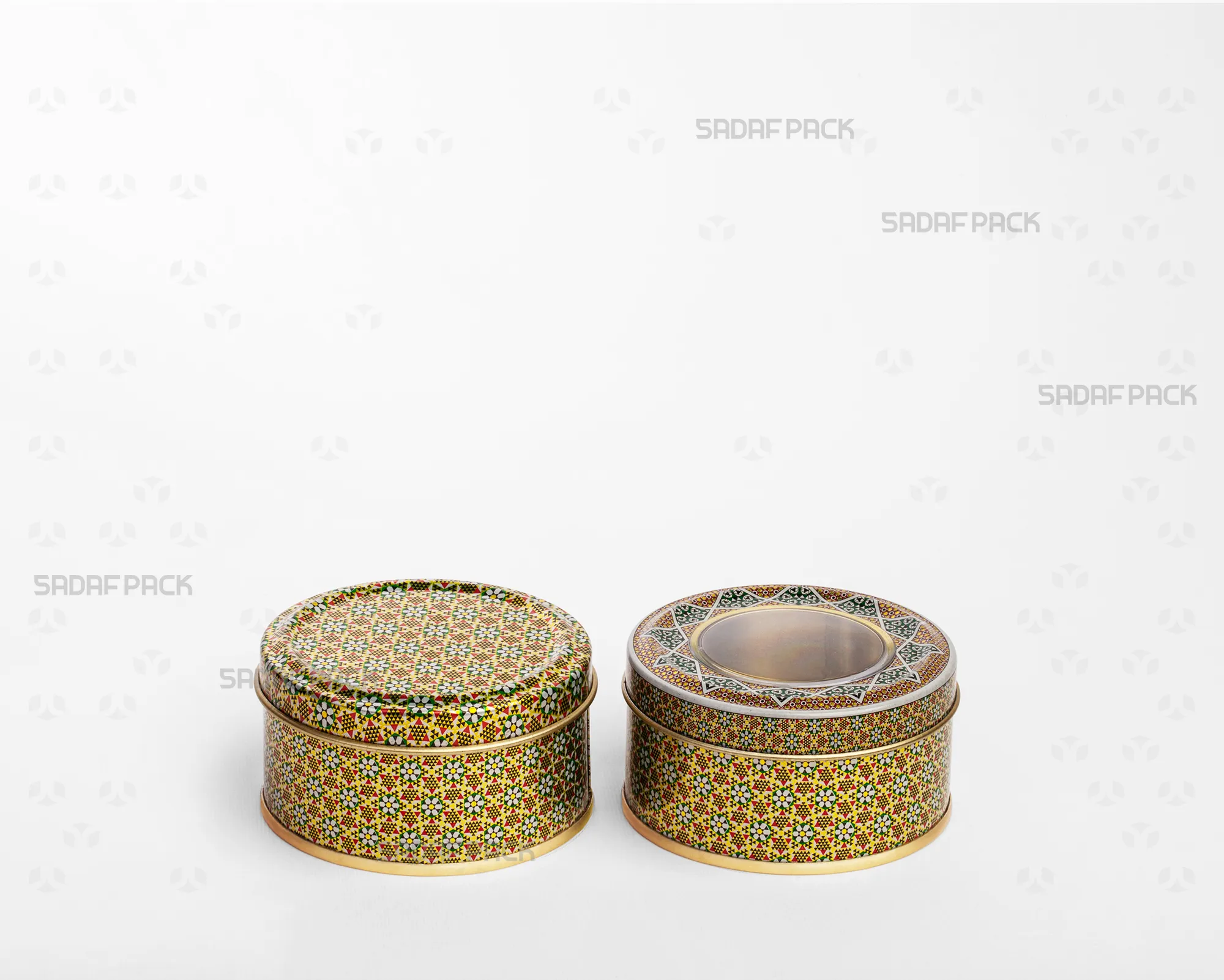 A side-by-side comparison in a three-quarter view of two Sadaf Pack 7cm by 3cm metal tins with the Green Khatam pattern, both closed, showing the version with a polycrystal window lid and the version with a solid lid.