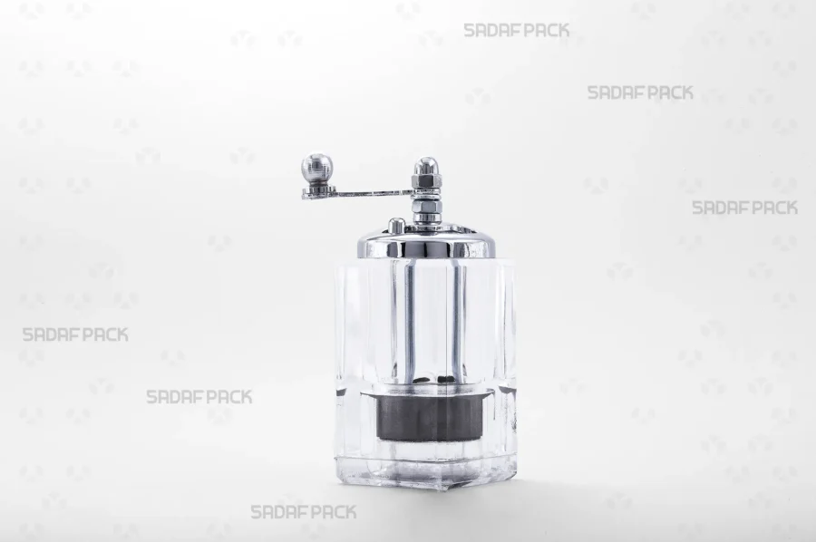 A front view of the Sadaf Pack Simple Morvarid crystal saffron grinder, highlighting its transparent body, chrome-plated metal cap, and ergonomic rotary handle, expertly designed for grinding saffron into a fine, uniform powder.