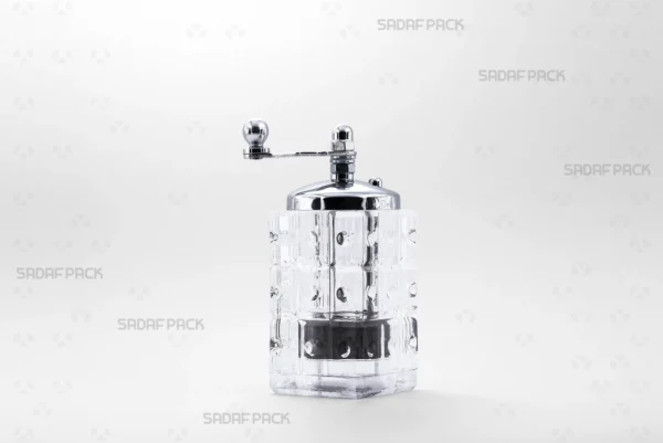 Front view of the Sadaf Pack Patterned Morvarid crystal saffron grinder, showcasing its transparent glass body, chrome-plated metal cap, and ergonomic rotary handle, designed for grinding fine saffron powder.