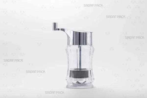 Front view of the Sadaf Pack Crystal Saffron Grinder Sadaf model, showcasing its transparent body and chrome-plated rotary handle, designed for milling fine saffron powder.