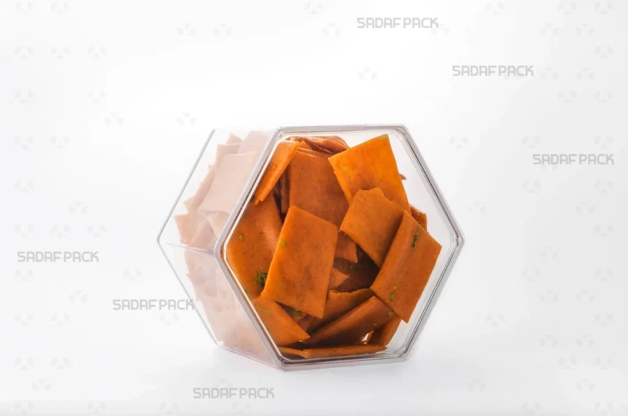 An elegant three-quarter angle view of the export-quality Hexagon Tall container filled with Persian Saffron Brittle, highlighting its excellent product visibility.
